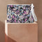 Rectangular wristlet clutch featuring a dark background with colorful bats, skulls, eyeballs, and vampire mouths. White strap and gold zipper visible.